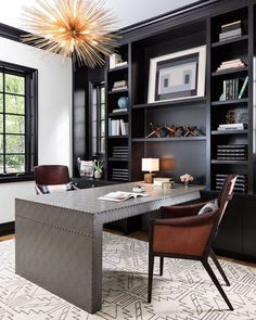 an office with black bookcases, leather chairs and a large table in the center