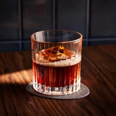 a glass filled with liquid sitting on top of a wooden table