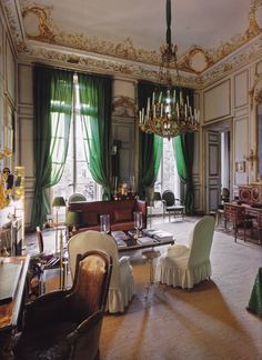 an ornate living room with green curtains and chandelier hanging from the ceiling,