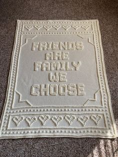 a white crocheted afghan with the words friends are family and friends written on it