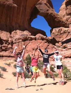 four people jumping in the air with their hands up