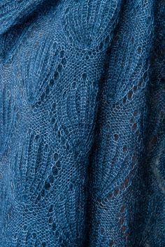 a blue knitted shawl with holes in the middle and an intricate design on it