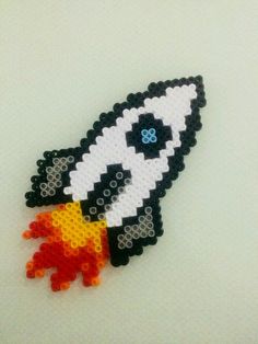 a beaded brooch with a black and white rocket ship on it's side