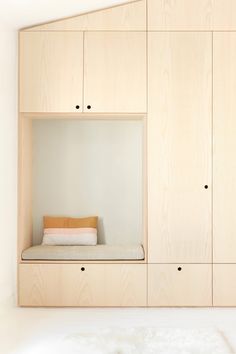 an empty room with wooden cabinets and a bed in the corner, as well as a white fur rug on the floor