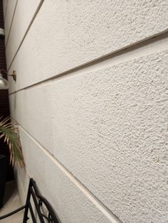 a bike leaning against a white wall next to a potted plant