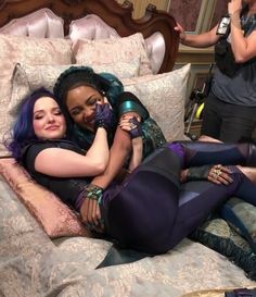 two women are laying on a bed and one is hugging the other while another woman takes a selfie