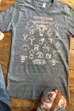 a gray t - shirt with the words texas on it next to shoes and a pair of slippers