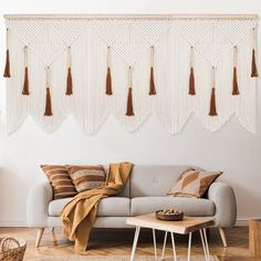 a living room with a gray couch and tassels hanging on the wall above it