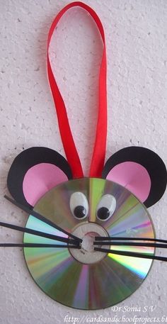 a mouse hanging on the wall with a cd attached to it's face and red ribbon around its neck