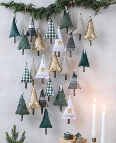 a christmas tree decoration hanging from a wall next to a lit candle and some pine cones