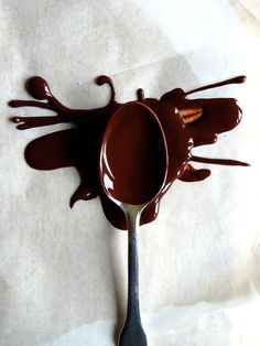 a spoon filled with melted chocolate on top of paper