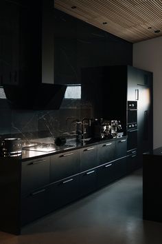 a large kitchen with black cabinets and marble counter tops is lit by the light coming through the window