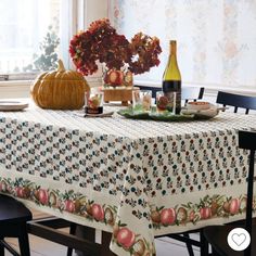 the table is set with an apple and pumpkin design on it, along with two bottles of wine