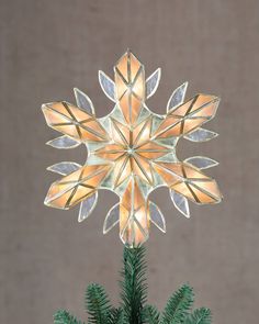 a glass snowflake ornament sitting on top of a christmas tree