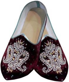 pair of maroon velvet shoes with white and gold embellishments on the sole