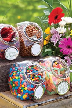 several jars filled with candy and flowers on top of a wooden table