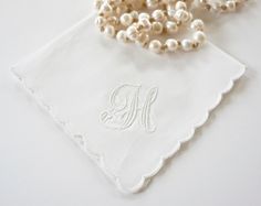 a white handkerchief with a monogram on it and pearls hanging from the neckline