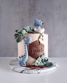 a cake decorated with dinosaurs and leaves on top of a white table next to a gray wall