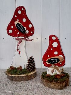 two red and white mushrooms sitting on top of a wooden stump next to a pine cone