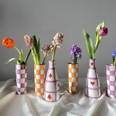 four vases with flowers in them sitting on a white tablecloth covered table cloth