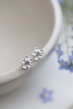 Sweet Little Solid Silver Forget-Me-Not Earrings. With beautiful Cornflower Blue Sapphire centres. Adding that gorgeous touch of blue.  The forget-me-not flowers hold meaning for me personally as the icon for The Alzheimers Society here in the UK. They flower late April, early May which is just gorgeous as we leave those dreary winter months. These dainty little stud earrings have been lovingly carved from a piece of wax and cast into these beautiful solid silver earrings. I included a special star on the rear of the flowers to echo the little star at their centres. The silver flower itself is recycled silver and fitted with the sterling 925 posts and butterflies. Each flower measure approx 8mm. These earrings can be personalised with birthstones etc should you wish. Forget Me Not Jewelry Sterling Silver, Pretty Stud Earrings, Safire Jewelry, Forget Me Not Earrings, Forget Me Not Jewelry, Cute Earrings Studs, Cute Silver Earrings, Earrings Studs Silver, Blue And Silver Earrings