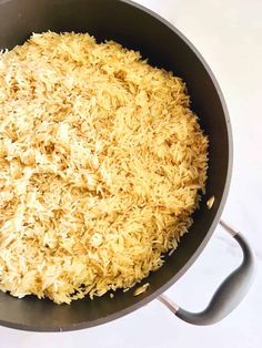 cooked rice in a frying pan on a white counter top with a spatula