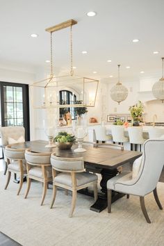 a dining room table with chairs and a chandelier hanging from it's ceiling