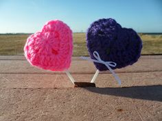 two crocheted heart shaped lollipops sitting on top of each other