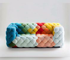 a multicolored couch sitting on top of a white floor next to a wall