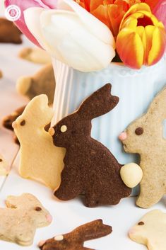 some decorated cookies in the shape of bunnies and rabbits on a table with tulips