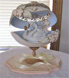 there is a white swan on top of a cake plate that is sitting on a table