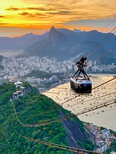 a cable car going up the side of a mountain with a city in the background