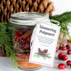 a jar filled with food sitting on top of a table next to pine cones and berries