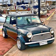 an old car is parked in front of some boats