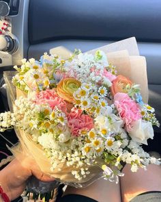 a woman is holding a bouquet of flowers in her lap while sitting in the car