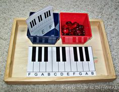 a wooden tray with piano keys and cherries in it on carpeted flooring