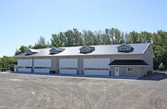 an empty parking lot with two garages on each side and trees in the background