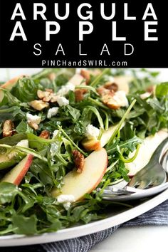 an apple salad with spinach and feta cheese is on a white platter