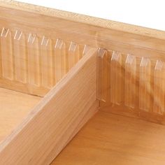 the corner of a wooden bed with clear plastic covering it's headboard and foot board