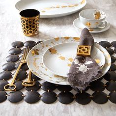 the table is set with black and white plates, silverware, and gold accents