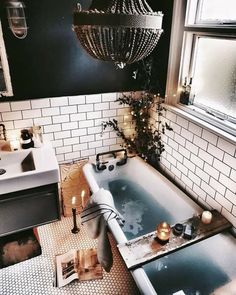 a bath tub sitting next to a window with candles on the floor and in front of it