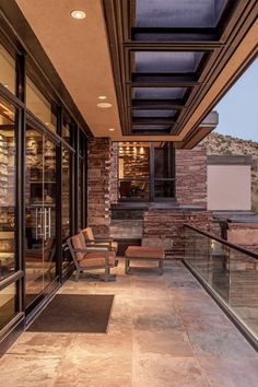 an outdoor patio with chairs and tables on the outside wall, overlooking mountains in the distance