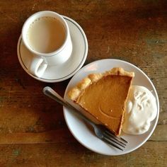 a piece of pie on a plate next to a cup of coffee