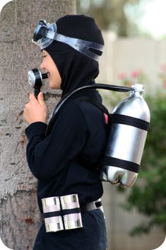 a young boy dressed as a soldier holding a water bottle and talking on a cell phone