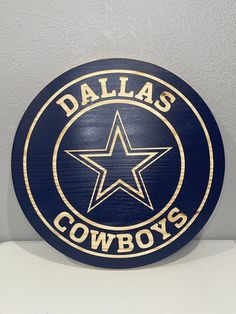 a wooden sign that says dallas cowboys on the side of a white wall with a blue background