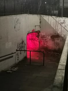 a dark tunnel with graffiti on the walls and red light at the entrance to it