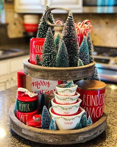 three tiered tray with christmas themed cups and trees on the top, sitting on a kitchen counter