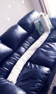 a blue leather couch with a white pillow on it's back and stars painted on the wall behind it