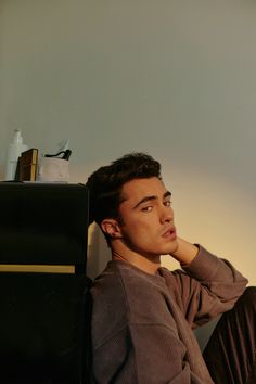 a man sitting on the floor with his hand under his chin and looking off into the distance