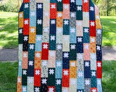 a quilt is hanging on the clothesline in front of some green grass and trees